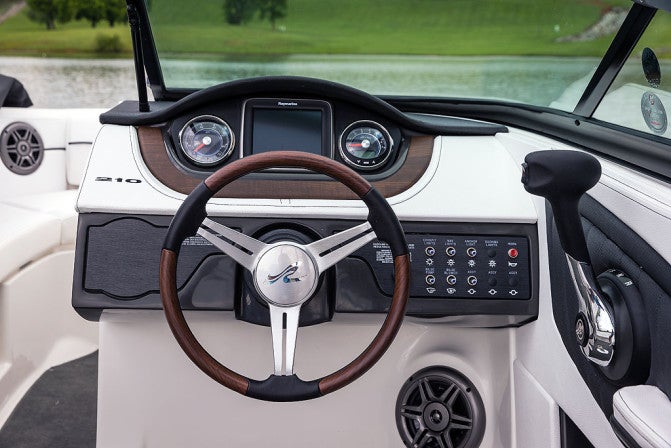 The 210 SLX helm is neatly laid out, with stainless trim and glass-lensed instruments.